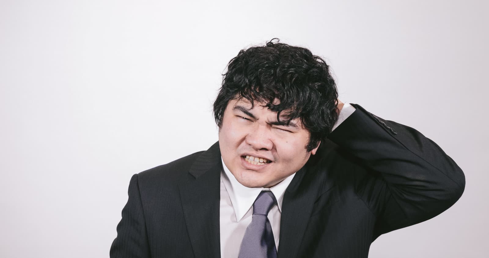 仕事のミスを思い出して悔しがるスーツ姿の男性
